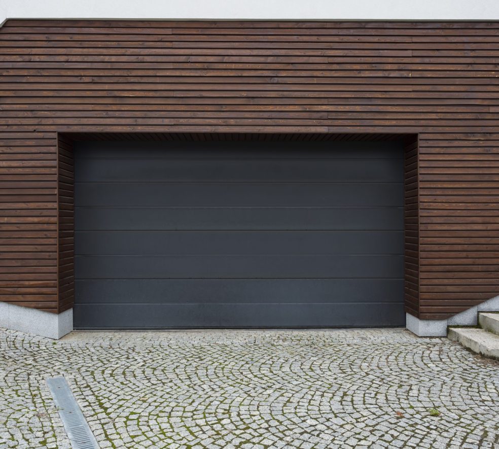 Big garage with black door and wooden wall in spachpuseious yard